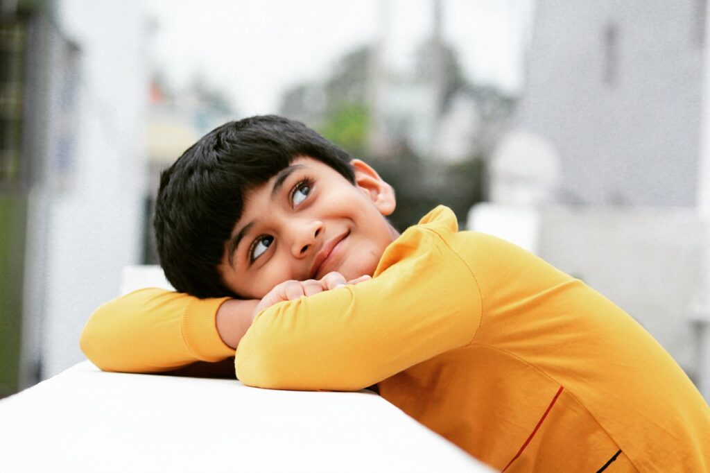 a boy resting his head on his arms and smiling